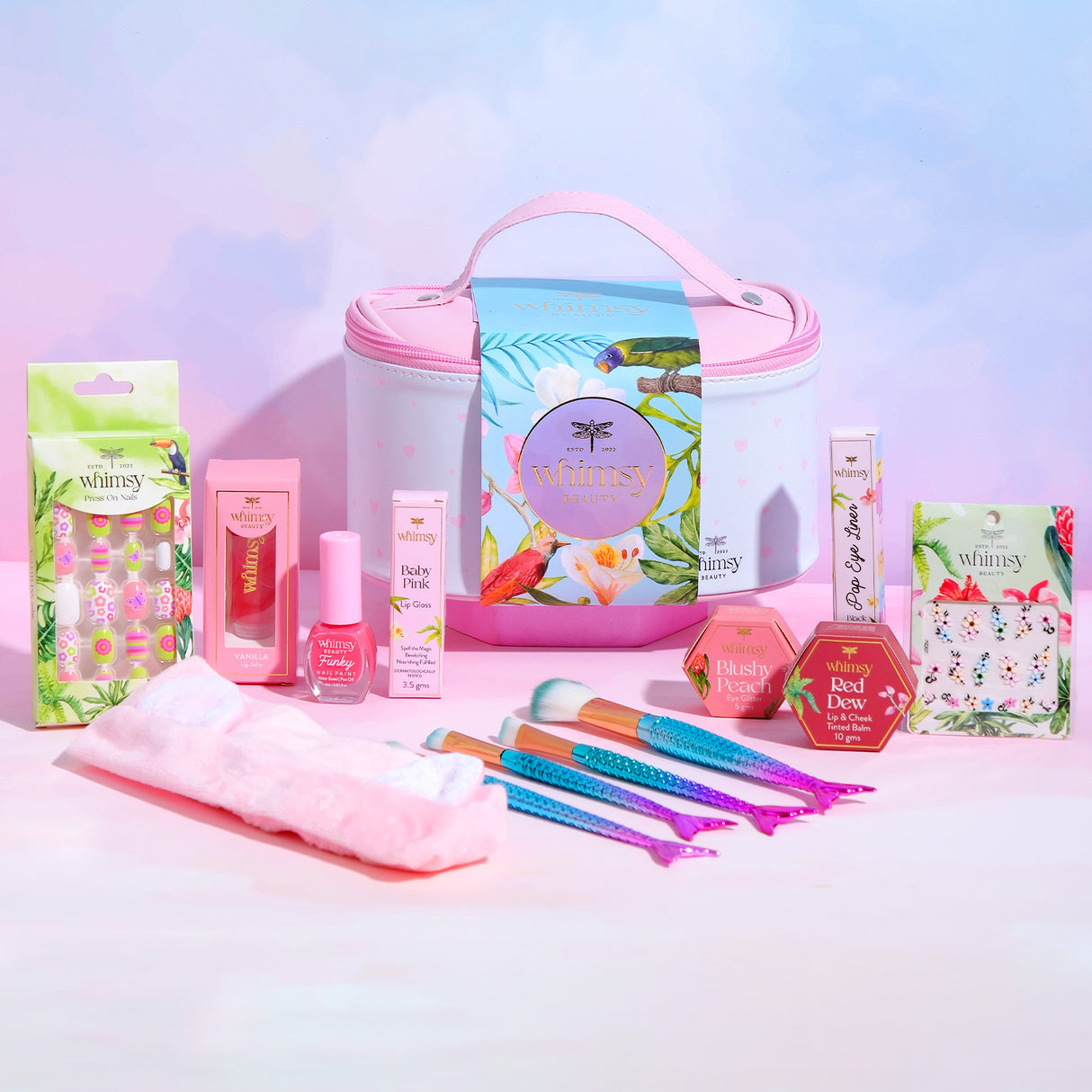 Collection of Whimsy beauty products including nail polish, hair ties, and a pouch on a gradient background