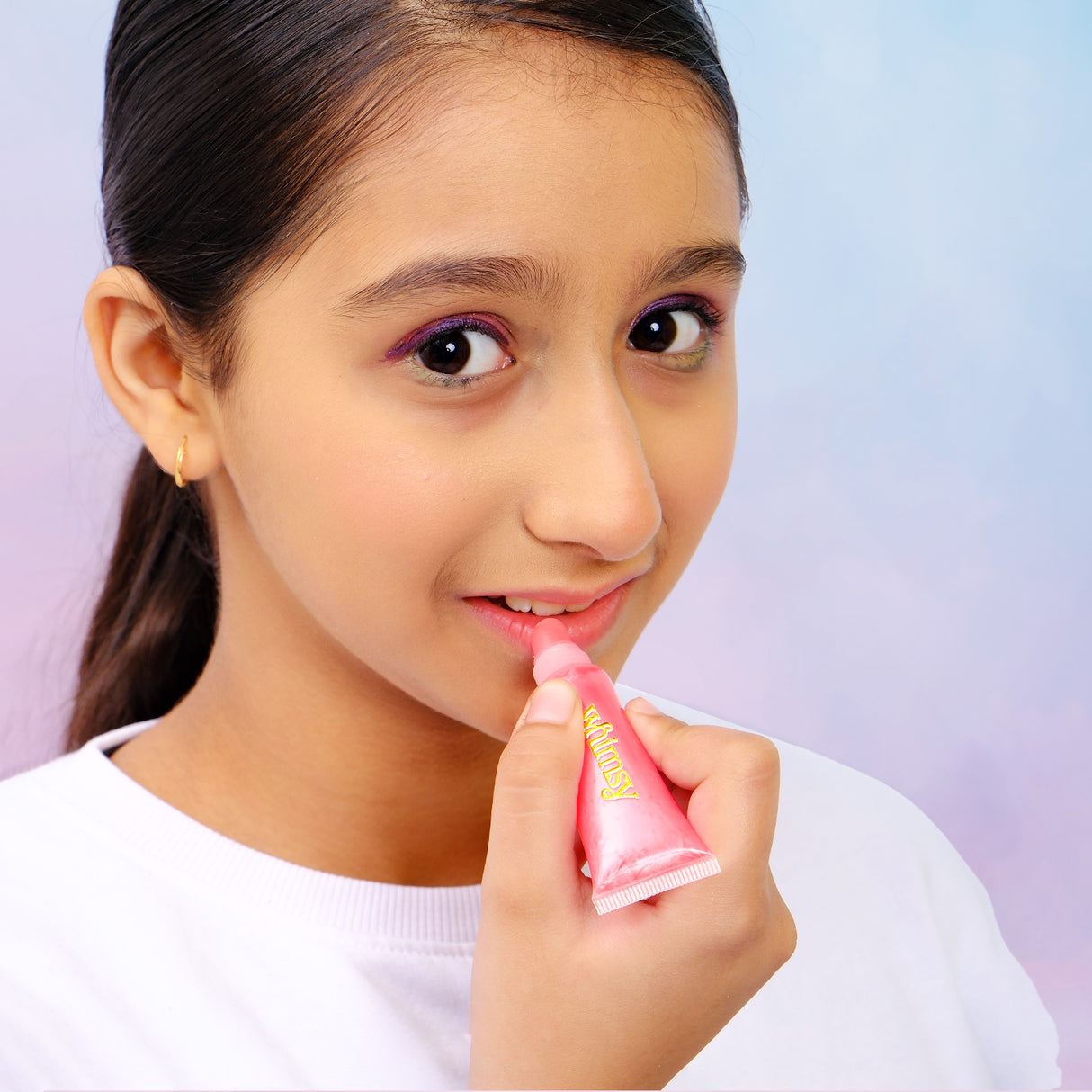 Girl applying pink lip balm with a blurred background