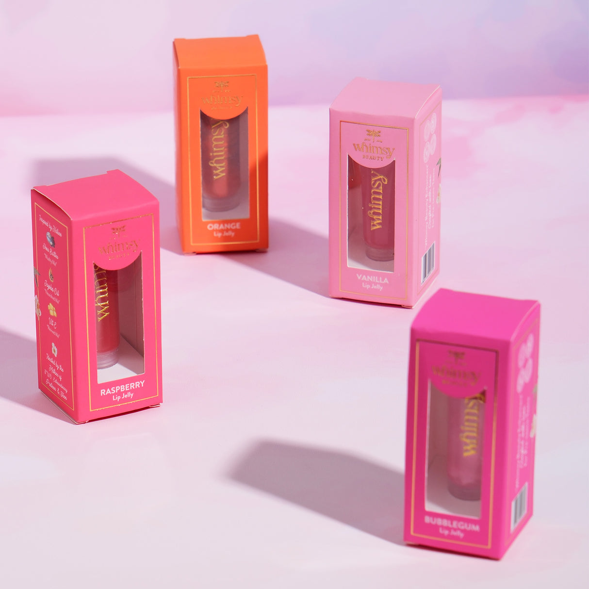 Four lip balm boxes in pink packaging with visible brand name on a light pink background