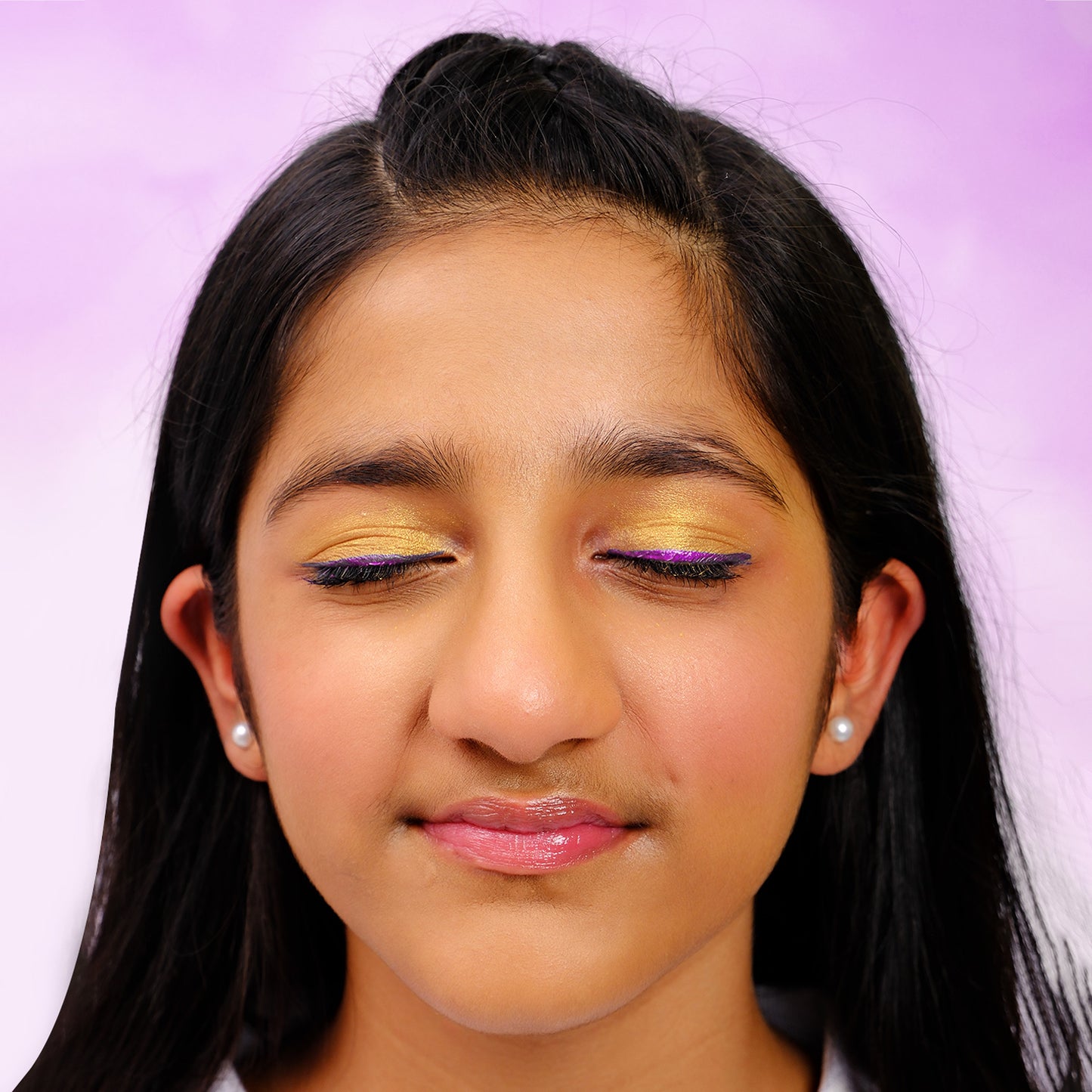 Close-up of a young girl with colorful eye makeup on a purple background