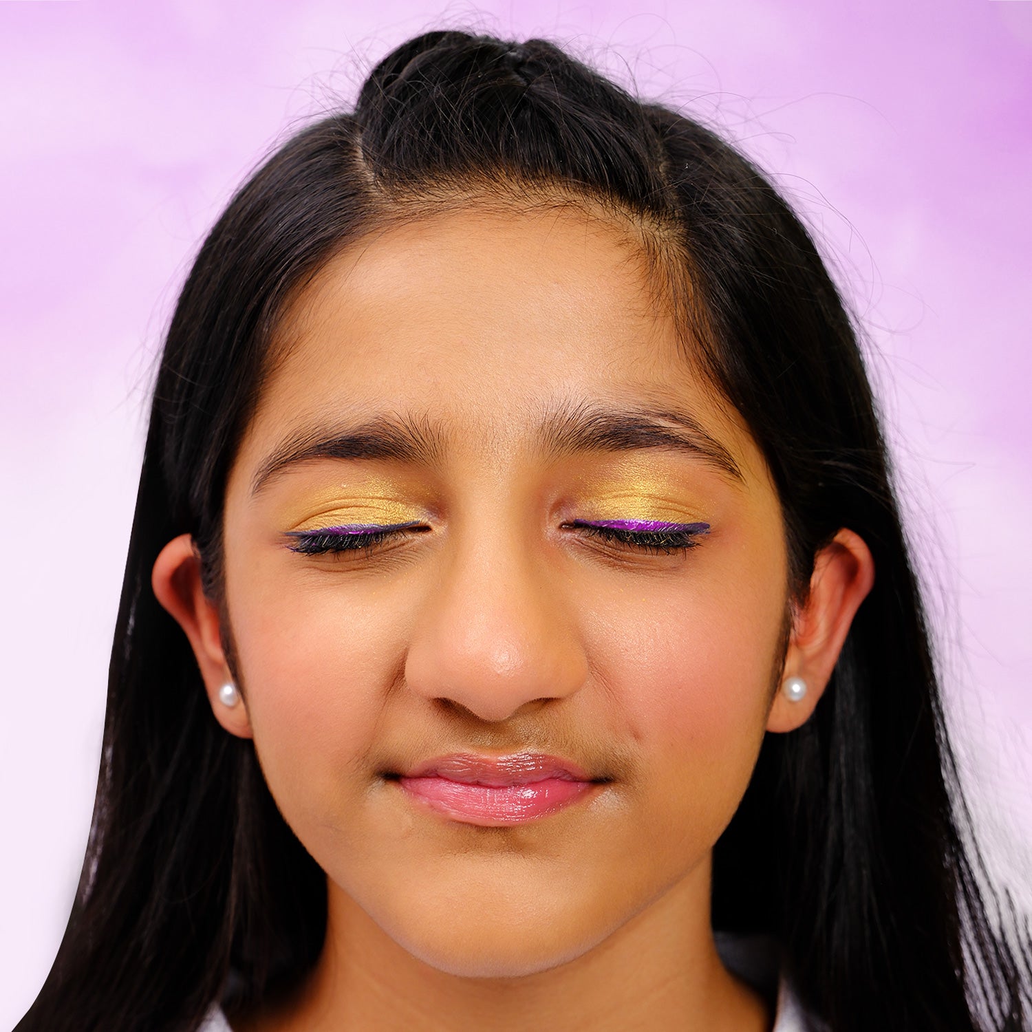 Close-up of a young girl with colorful eye makeup on a purple background