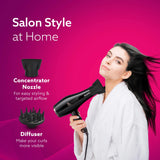 Woman using a hair dryer with concentrator nozzle and diffuser on a pink background