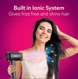 Woman using a hair dryer with ionic technology on a pink background